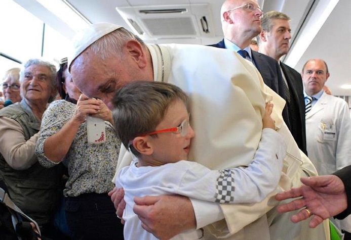 Fotografía cedida por el periódico vaticano L'Osservatore Romano que muestra al Papa mientras saluda a un niño durante su visita sorpresa a la Fundación Santa Lucía