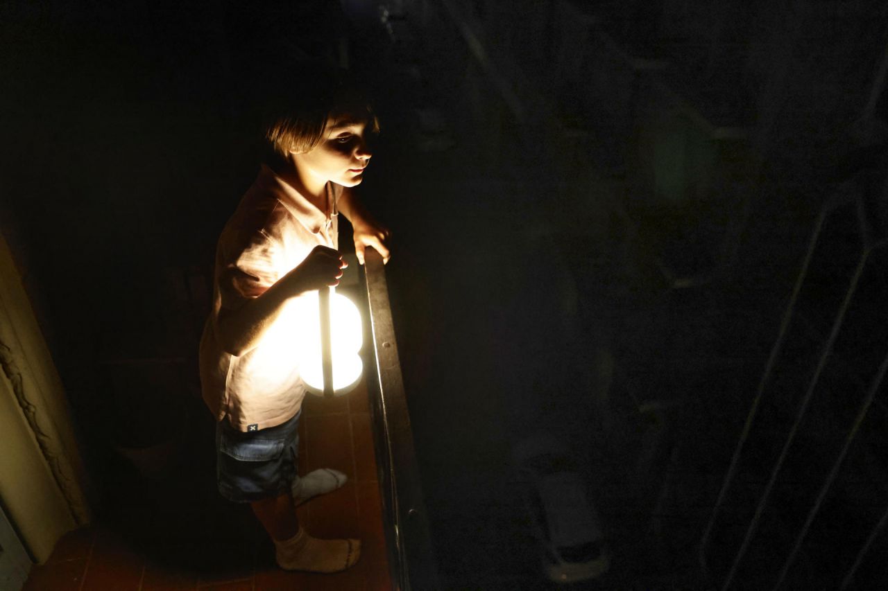 Un niño con una lampara mirá desde el balcón la calle todavía a oscuras esta madrugada en el centro de Barcelona durante el corte de suministro eléctrico que afecta este lunes a España y que ha dejado sin servicio el metro y el tranvía de Barcelona y toda