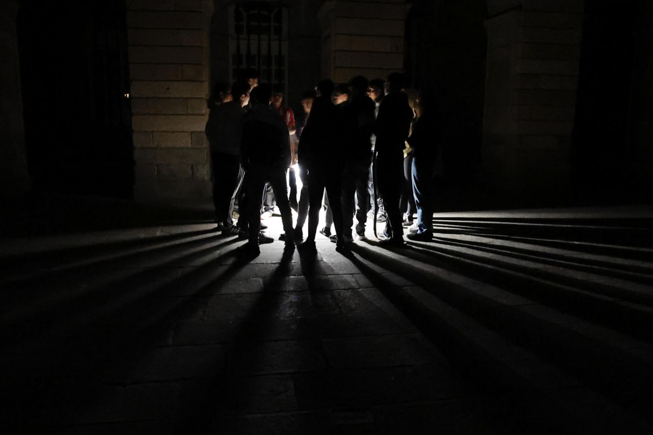 Jóvenes se reúnen frente a una catedral durante un apagón este martes, en Santiago de Compostela (España). 