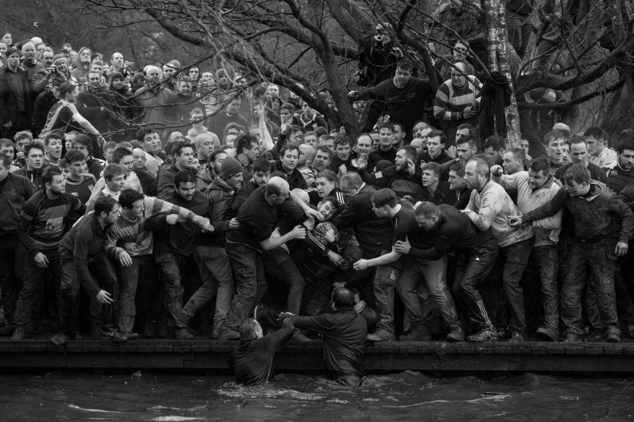 Los miembros de los equipos oponentes, los Up'ards y Down'ards, luchan por el balón durante el histórico y anual Torneo de Fútbol Royal Shrovetide en Ashbourne, Derbyshire, Reino Unido.
