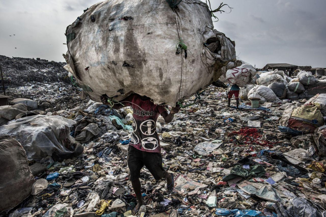 Un hombre carga de botellas de PET para reciclar, en el vertedero de Olusosun, Lagos, Nigeria. Más de 3.000 toneladas de residuos llegan diariamente a Olusosun. Más de 4.000 personas, muchas de las cuales viven en el lugar, hurgan en la basura cada día para recoger todo lo que se pueda vender o reciclar.