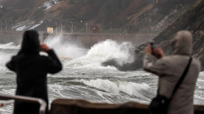 Una pareja fotografía el oleaje que rompe contra el Paseo Nuevo de San Sebastián.