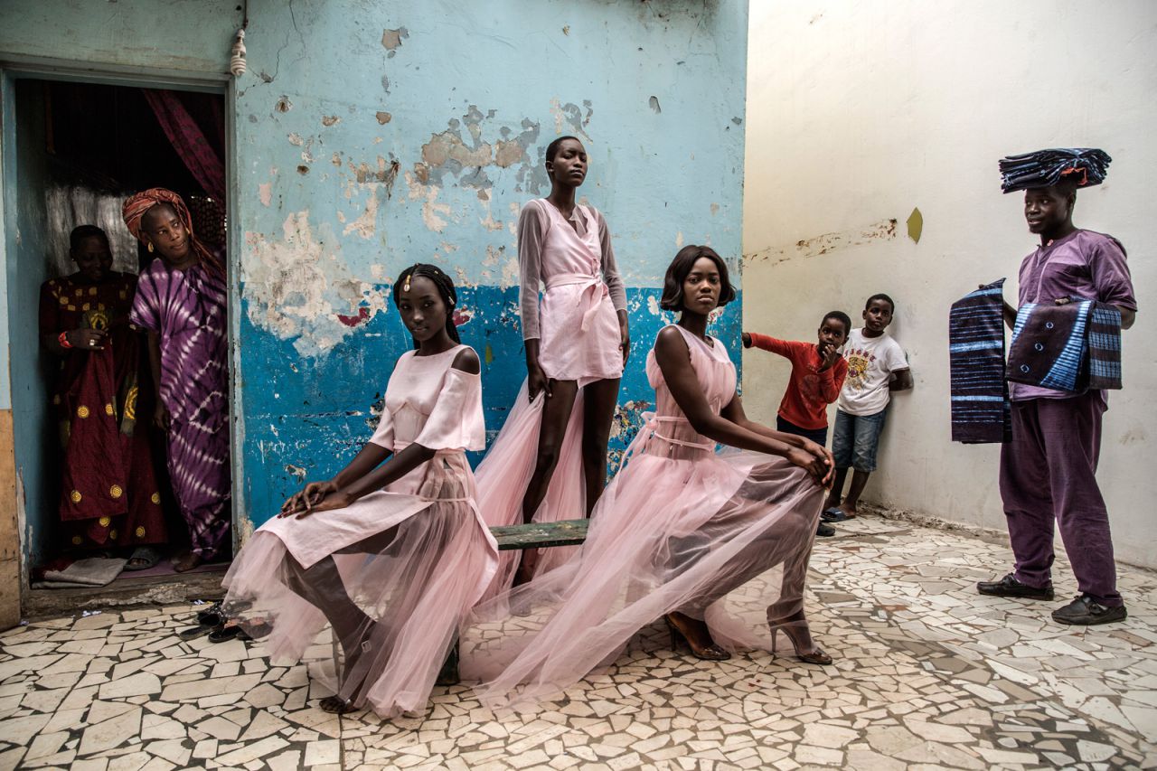 Diarra Ndiaye, Ndeye Fatou Mbaye y Mariz Sakho visten atuendos del diseñador Adama Paris, en el barrio de Medina en la capital senegalesa, Dakar, mientras los curiosos residentes miran.