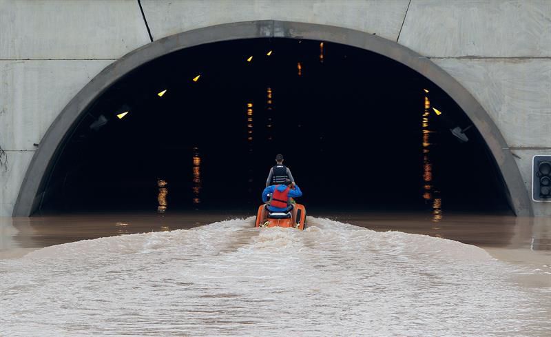 Varios miembros de los servicios de rescate cruzan en moto acuática la salida del túnel de la AP-7 a la altura del municipio alicantino Pilar de la Horadada.
