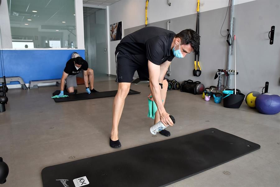 Dos entrenadores del centro deportivo SUMA en Almería desinfectan las instalaciones tras un entrenamiento personalizado con un cliente.