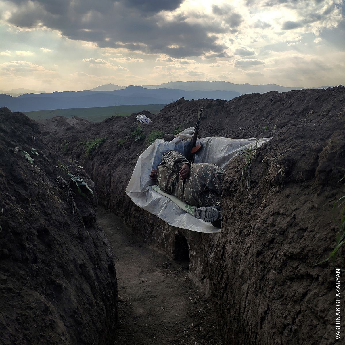Un soldado yace en una trinchera, descansando sobre una cubierta de plástico, en la parte noreste de Syunik, Nerkin Khndzoresk, Armenia.