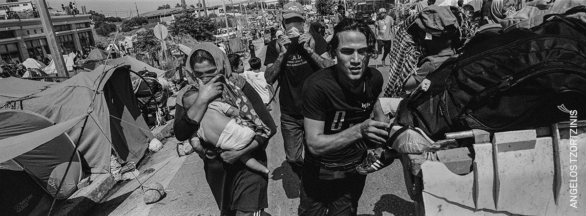 Las personas llevan sus pertenencias a lo largo de la carretera que va desde el campamento de refugiados de Moria quemado hasta la capital de la isla, Mitilene, en Lesbos, Grecia, el 14 de septiembre de 2020.