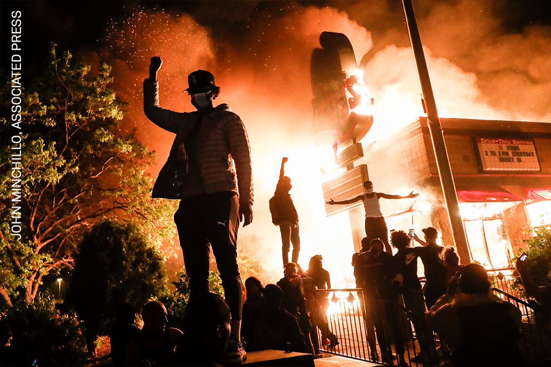Los manifestantes levantan los puños en desafío frente a un restaurante de comida rápida en llamas cerca de la estación del recinto de los oficiales que arrestaron a Floyd, en Minneapolis, Minnesota, EE. UU., el 29 de mayo de 2020.
