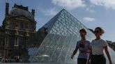 Dos personas caminan al lado del Museo del Louvre.