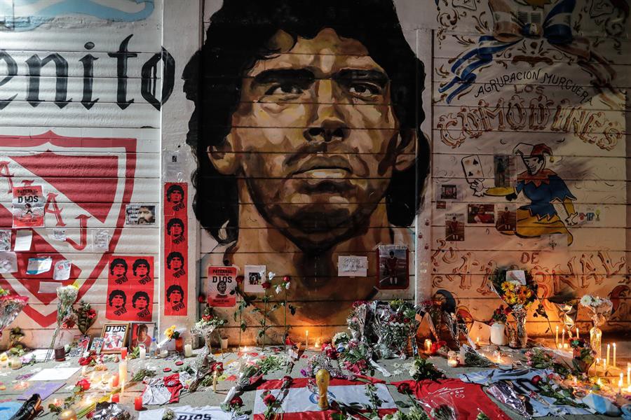 Ofrendas florales, banderas, velas y cartas que adornan a modo de altar un mural con la imagen de Diego Armando Maradona / EFE - Juan Ignacio Roncoroni