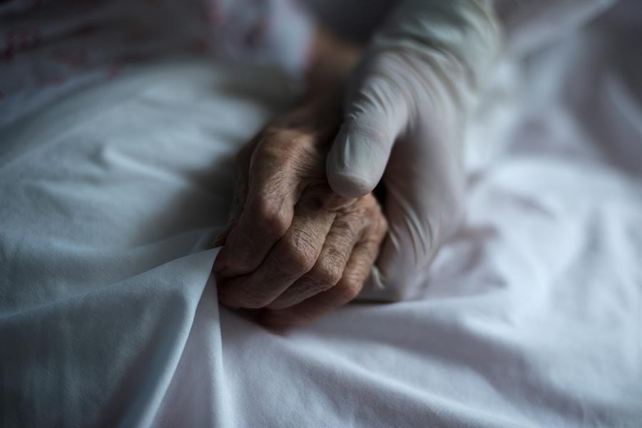Una trabajadora de la residencia de Celanova (Ourense) sujeta la mano de una residente / EFE - Brais Lorenzo