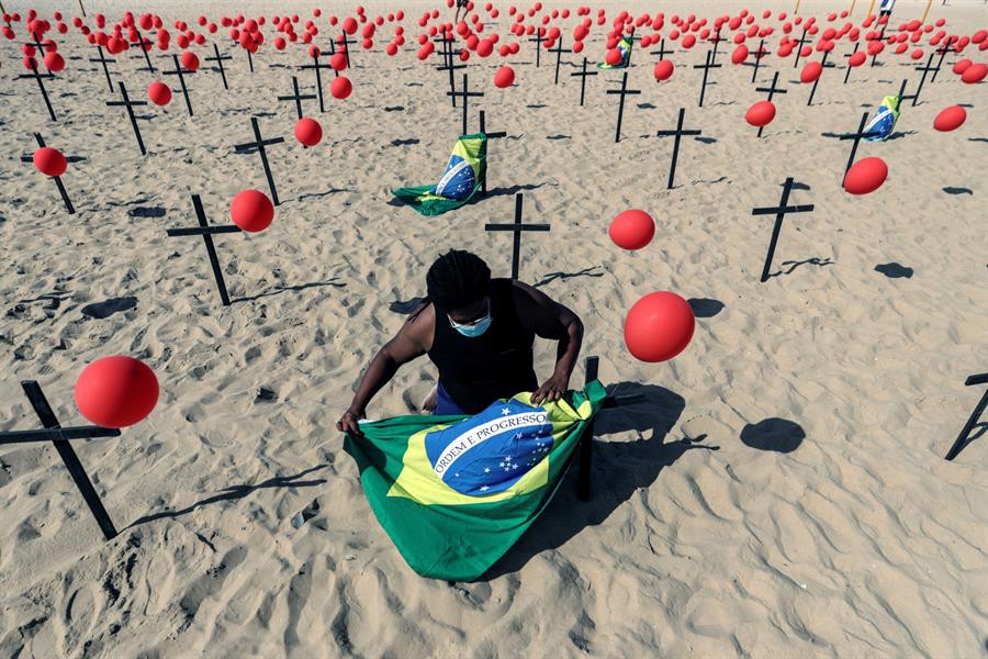 Un activista instala una bandera de Brasil en una representación escénica de la ONG Río de Paz por las víctimas de la Covid-19 / EFE - Antonio Lacerda