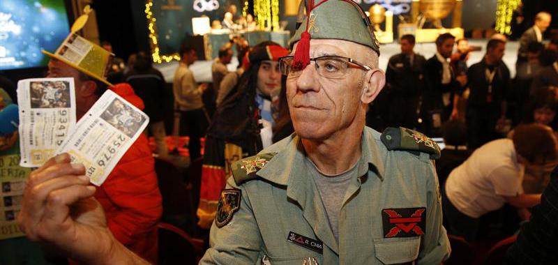  Uno de los asistentes, ataviado con indumentaria de la Legión, muestra sus décimos mientras espera en el interior del Teatro Real