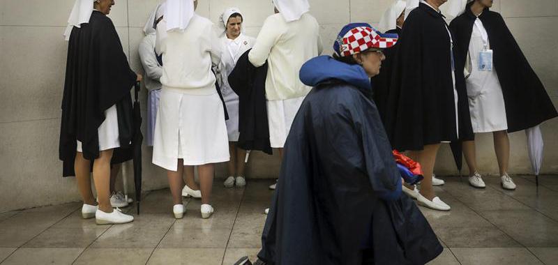 Una peregrina reza junto a un grupo de monjas en Fátima