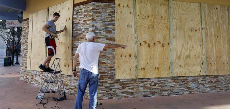 Los propietarios de un establecimiento protegen las ventanas con tablones ante la inminente llegada del huracán Irma, en Miami, Florida.