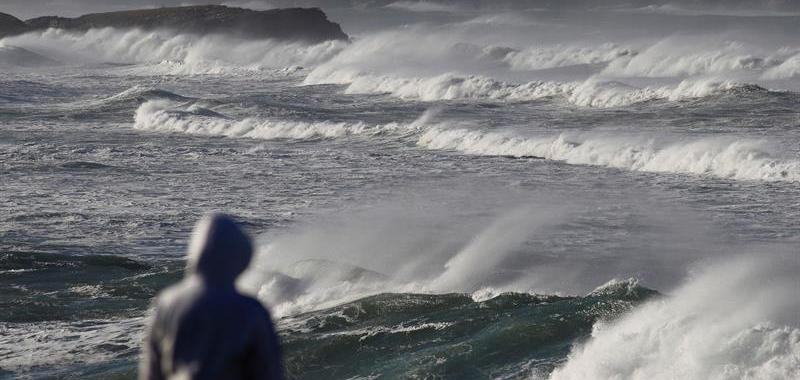 Una mujer mira el mar agitado en la costa de Barreiros.