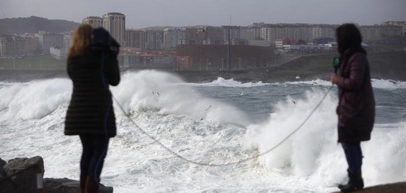 Dos reporteras de televisión realizan su trabajo sobre los efectos del temporal en la ciudad de A Coruña.