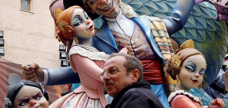 Un hombre pasa ante unos Ninots que representan a un grupo de falleras.
