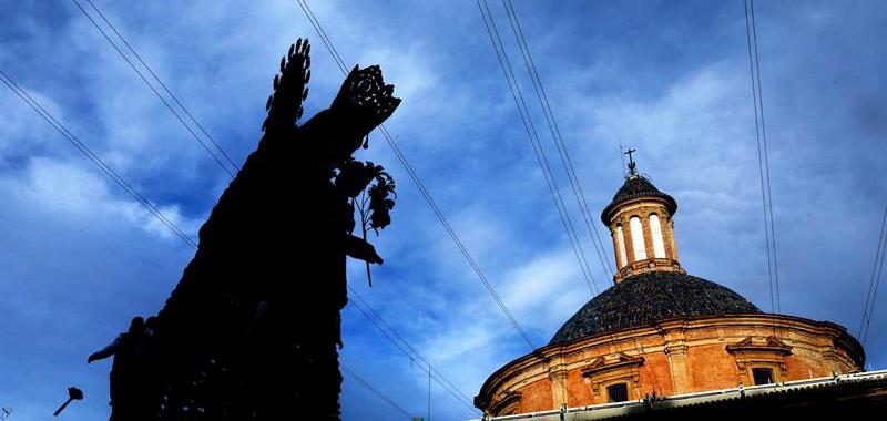 Dos "Vestidors" (i) se lanzan un ramo de flores para formar el manto de la patrona de Valencia, conocida popularmente como la "Geperudeta", ante la Basílica de la Virgen.