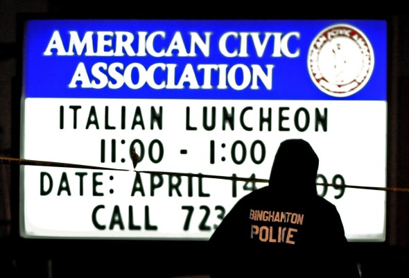 Un oficial de policía camina junto a un aviso a las afueras del edificio de la Asociación Cívica Americana de Binghamton. Efe