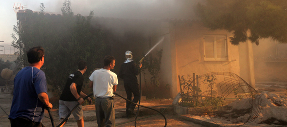 Un equipo de bomberos y voluntarios lucha contra las llamas en Kato Souli, a 40 kilómetros de Atenas. EFE