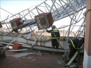Los bomberos retiran en Madrid un cartel con peligro de caer a la calle. Efe