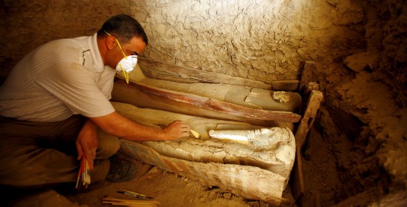 Un arqueólogo egipcio limpia un féretro de madera que contiene una momia cubierta con un trapo de lino, en la pirámide Illahun de la localidad egipcia de Faiyum, a 130 kms al suroeste de El Cairo. Efe