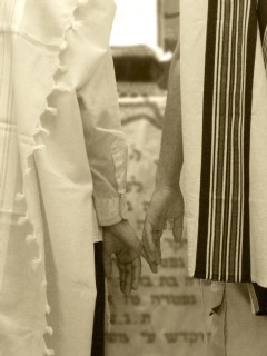 Dos varones ataviados con el manto religioso para la oración (talit) acariciándose cariñosamente las manos, firmada por Dror (nombre ficticio). (EFE)