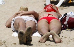 Dos personas toman el sol en la playa del Postiguet en Alicante