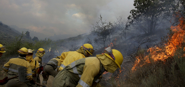 Medios terrestres y aéreos trabajan en la extinción de un incendio forestal declarado esta tarde en una zona de pino y monte bajo del término municipal de Serradilla del Llano. EFE