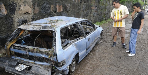 Salvadoreños observan un coche arrastrado por la lluvia (Efe)