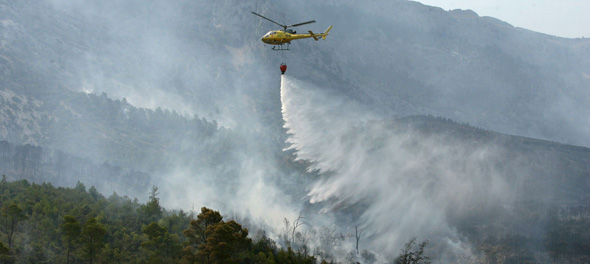 Un helicóptero arroja agua en la zona del frente del incendio de Horta de Sant Joan (Tarragona), en la carretera de Prat de Compte, donde viven unas 200 personas. EFE