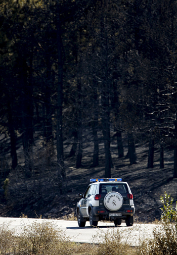 Un coche de la Guardia Civil circula por una carretera de la localidad turolense de El Pobo, donde se declaró anoche uno de los incendios forestales que han calcinado miles de hectáreas en la provincia de Teruel. EFE